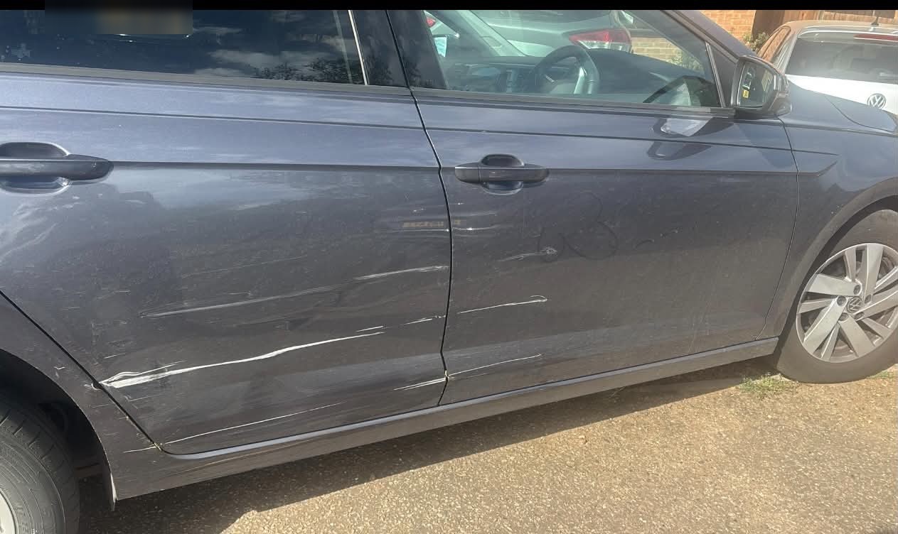 Long scratches along both doors of a grey hatchback, before the repair